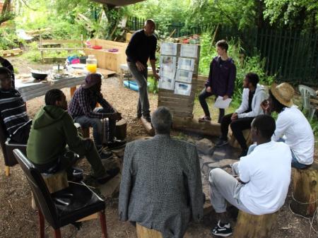 Imagrints, refugees and voluntees sat outside learning and training